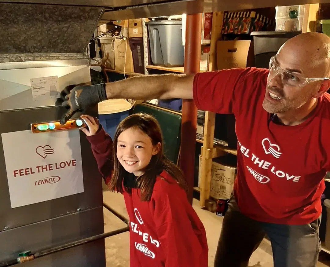HVAC tech and a Feel The Love recipient posing with the Lennox-donated HVAC unit.