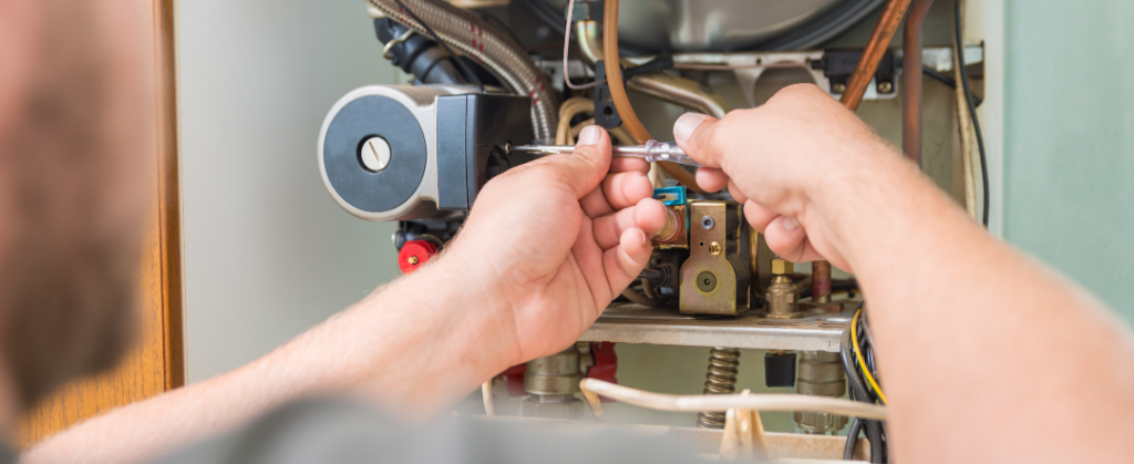 A stock photo of someone fixing an furnace from canva for our cracked heat exchanger blog post.