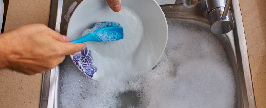 Stock image of someone washing dishes with the faucet off from canva for Air Experts' Reduce Your Water Usage blog post.